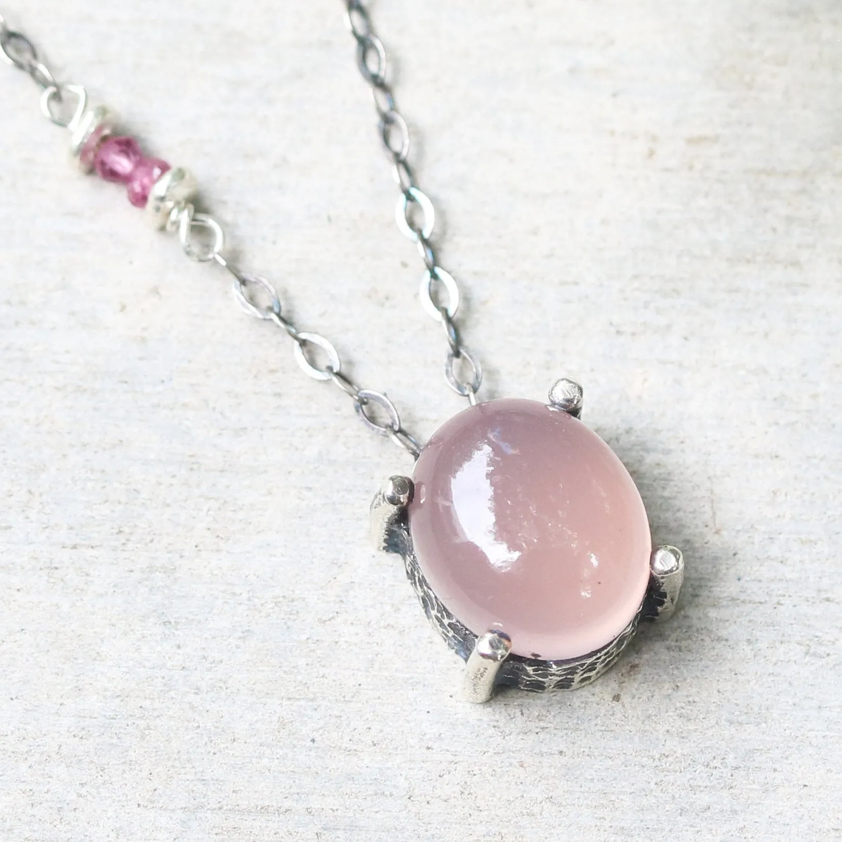 Oval cabochon rose quartz necklace in silver bezel and prongs setting with pink multi-sapphire beads secondary on oxidized silver chain