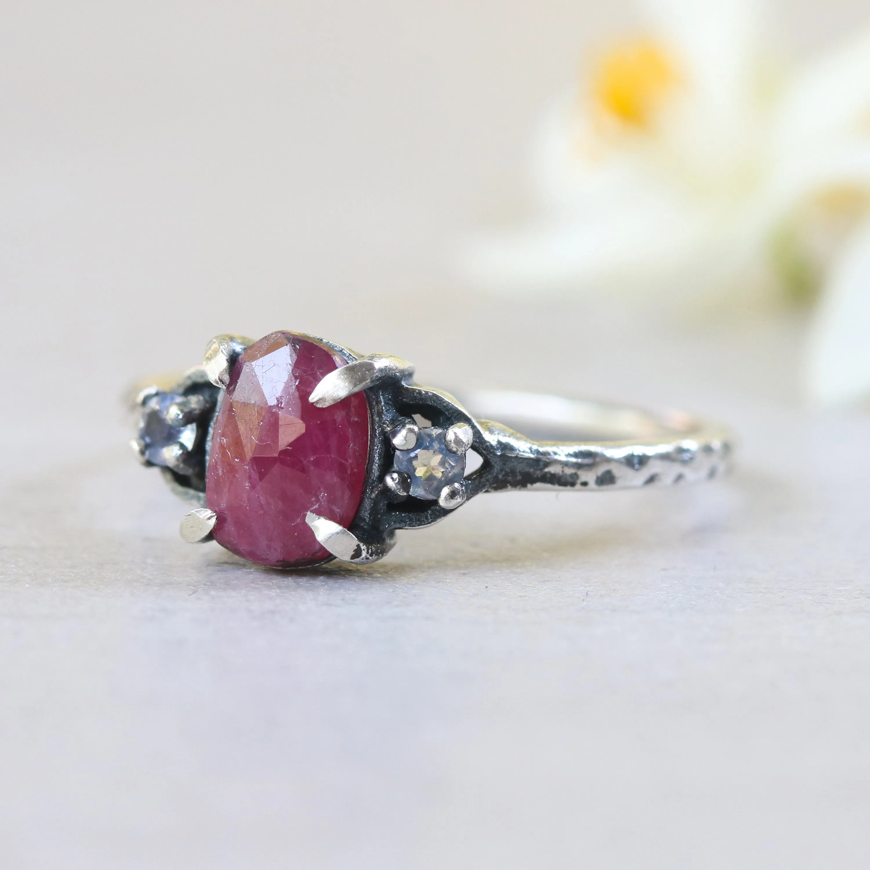 Oval ruby ring with tiny round faceted moonstone side set gems in prongs setting