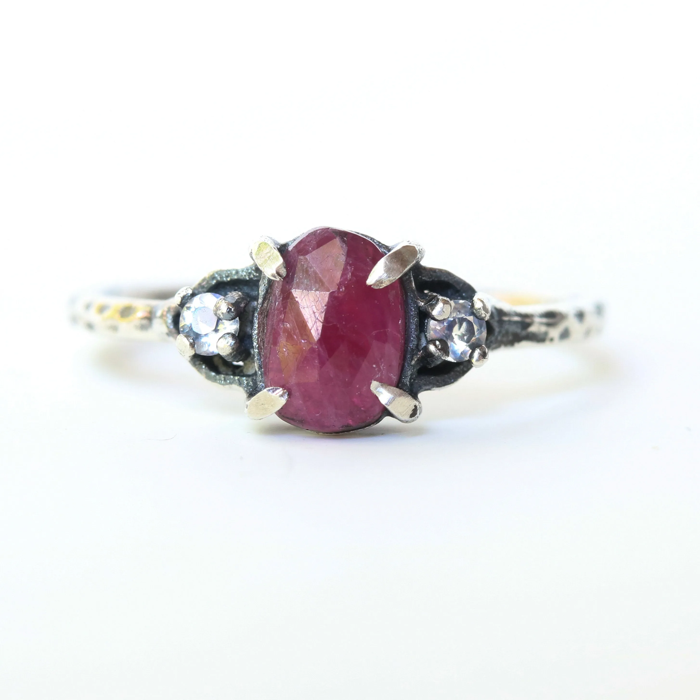 Oval ruby ring with tiny round faceted moonstone side set gems in prongs setting