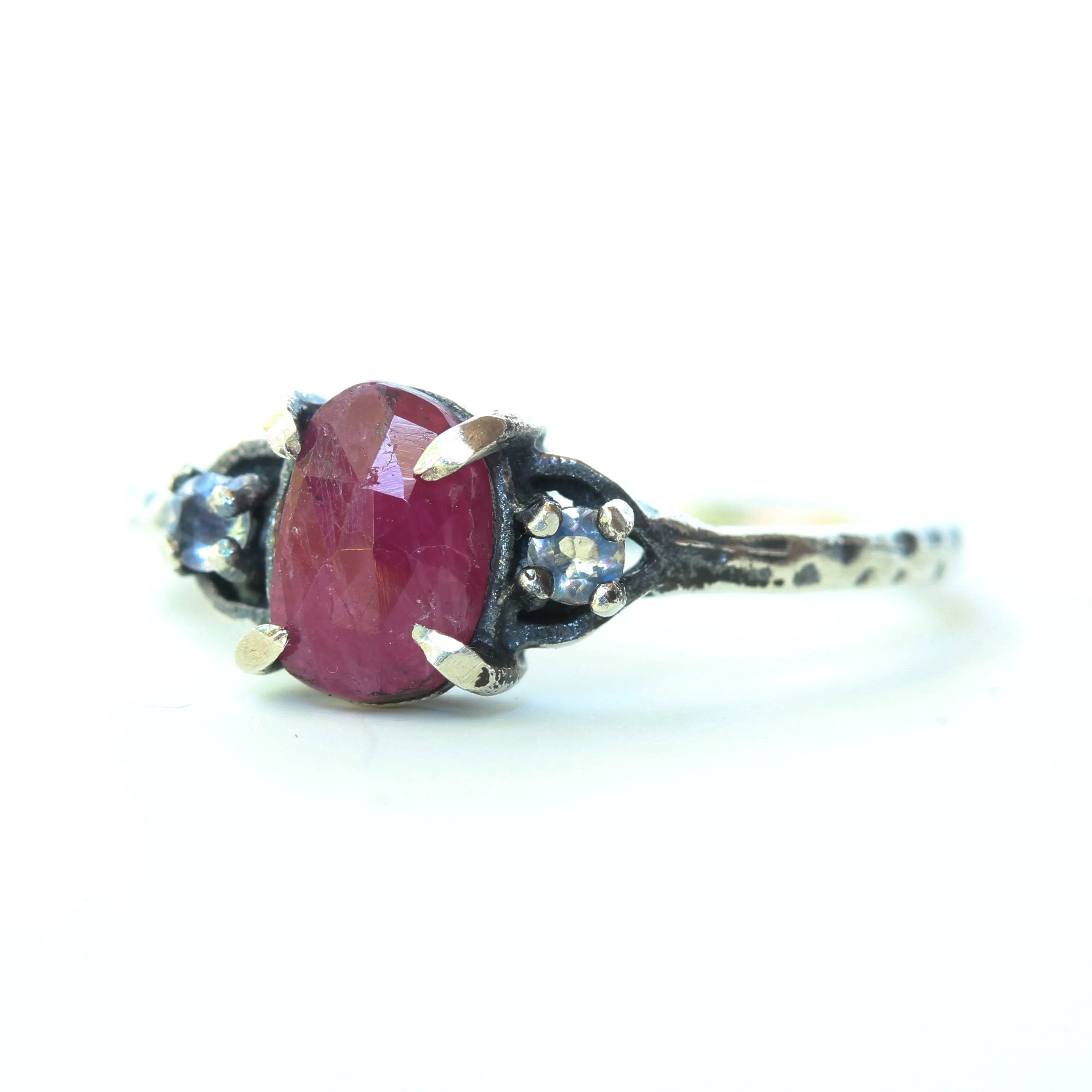 Oval ruby ring with tiny round faceted moonstone side set gems in prongs setting